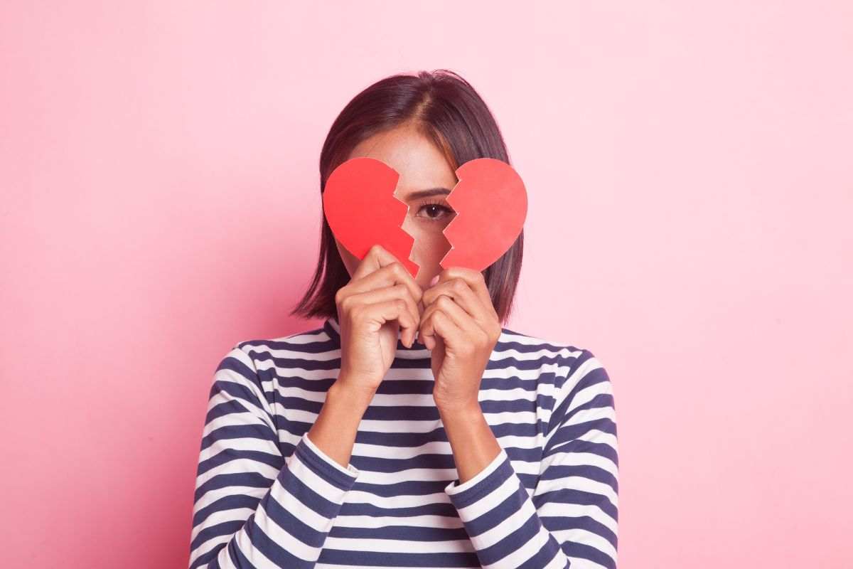 ragazza con cuore di carta spezzato in mano