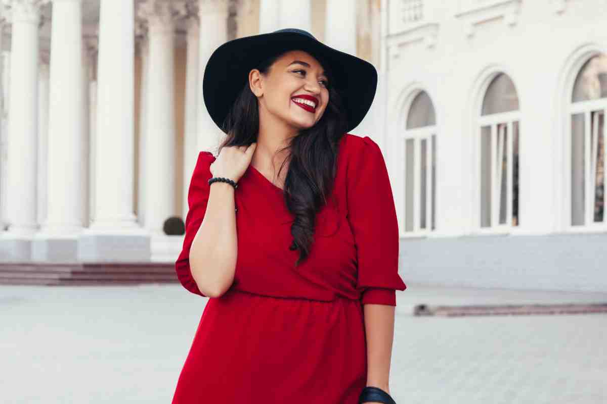 Donna in abito rosso e cappello, esempio di come vestirsi con la taglia 48 ed essere alla moda