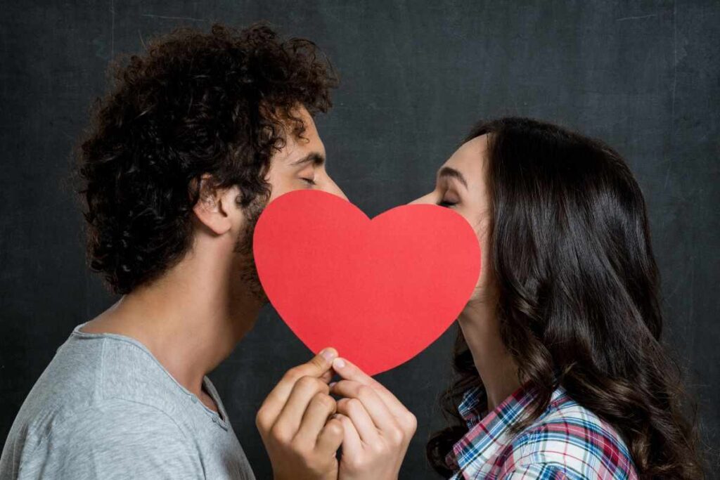 coppia che si bacia con cartoncino a forma di cuore