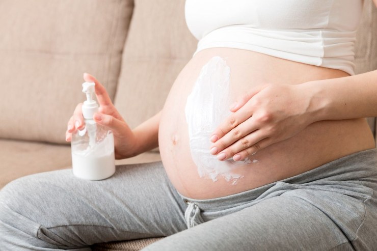 donna incinta che mette crema sul pancione