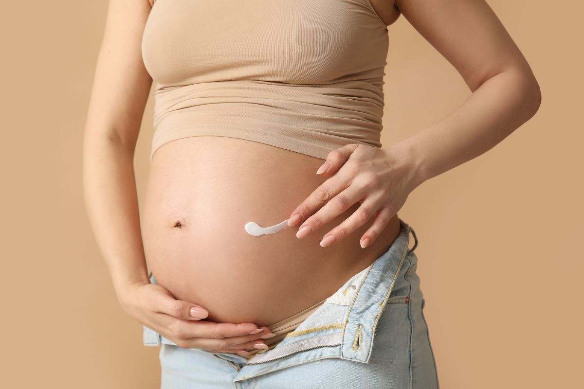 donna incinta che mette crema sul pancione