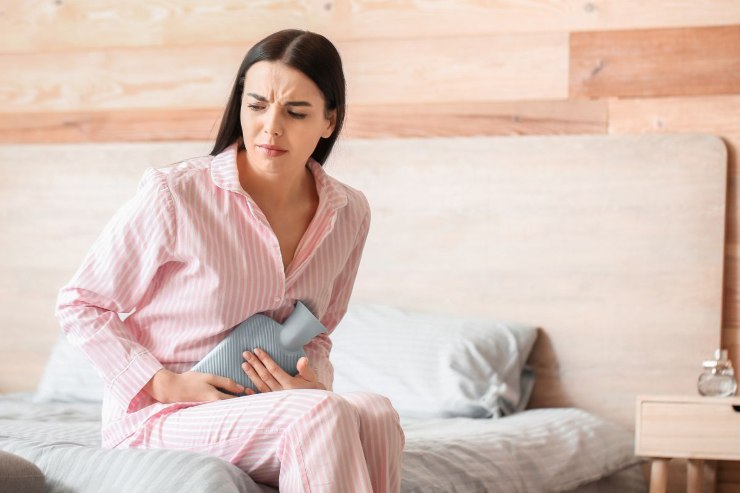 ragazza con borsa dell'acqua calda sulla pancia