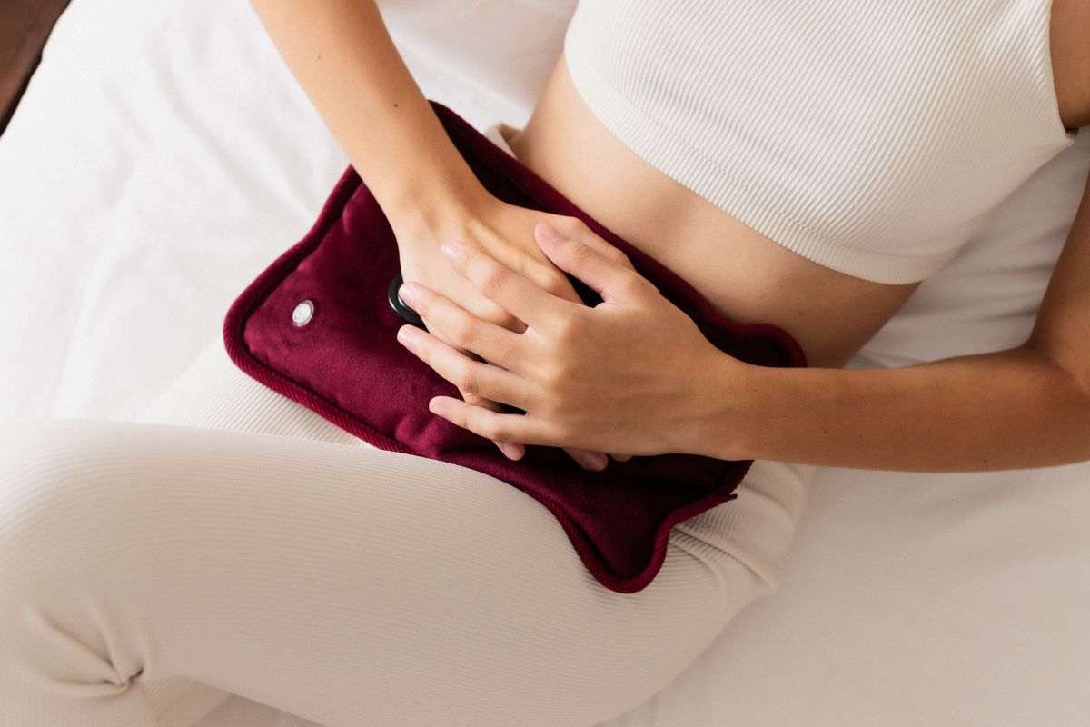 ragazza con borsa dell'acqua calda sulla pancia