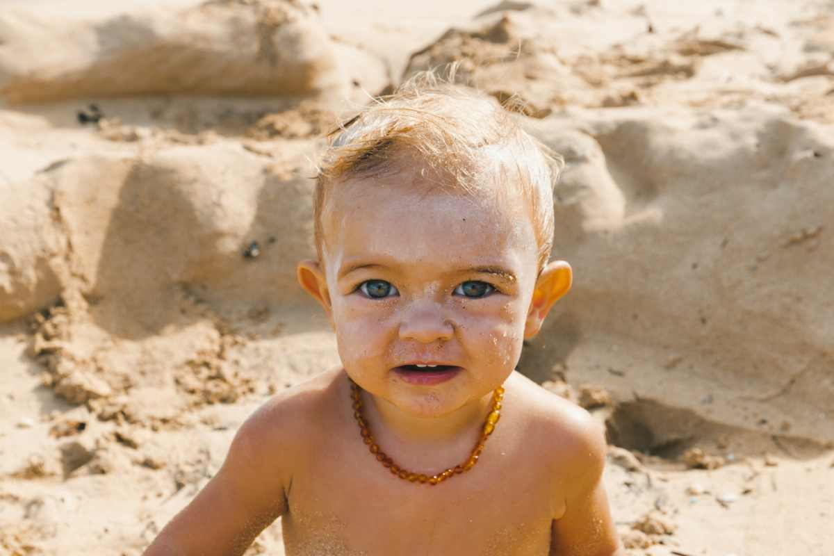 mamma spalma crema solare sul viso della bambina