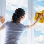donna che pulisce i vetri delle finestre