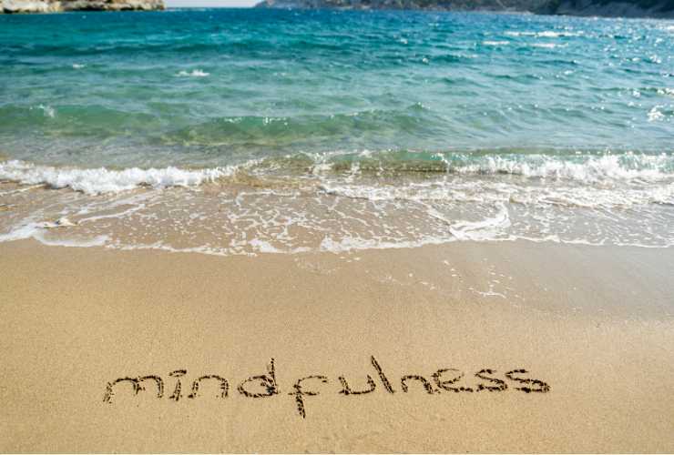 parola mindfulness scritta sulla sabbia in riva al mare