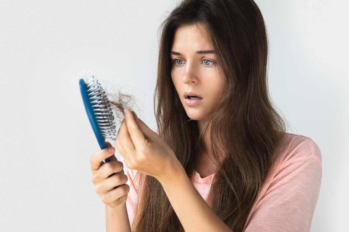 Donna che guarda spazzola con capelli stupita