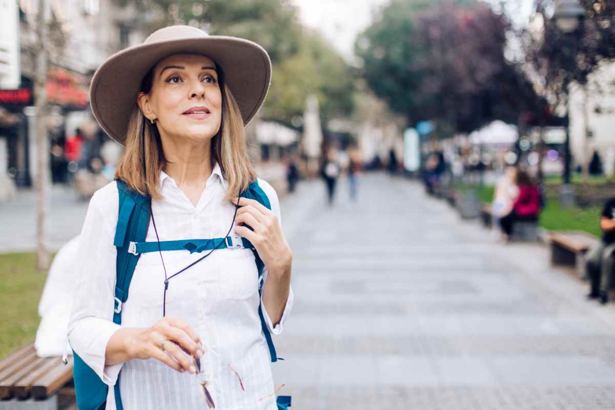 donna over 40 con zaino in spalla e cappello