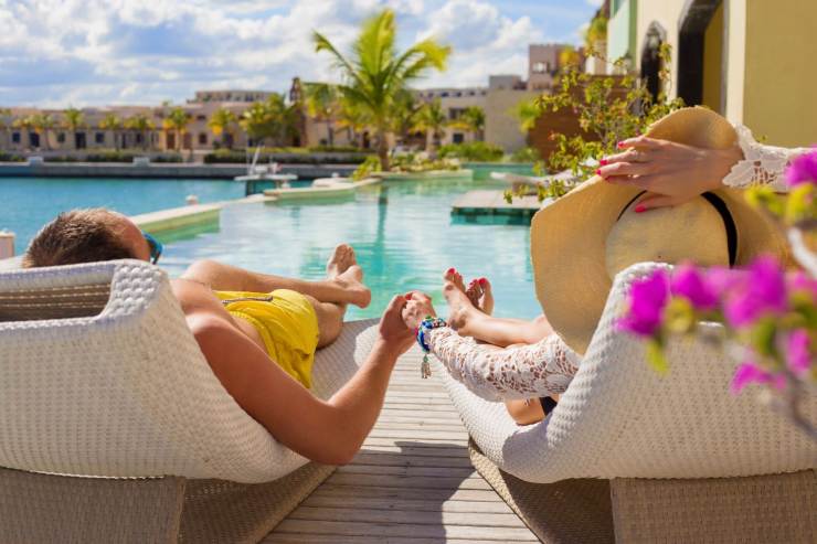 coppia che si dà la mano sui lettini in piscina