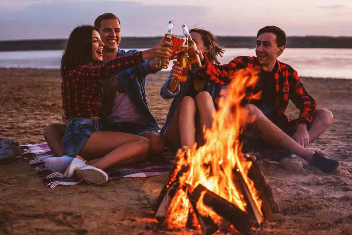 ragazzi che brindano davanti ad un falò in spiaggia