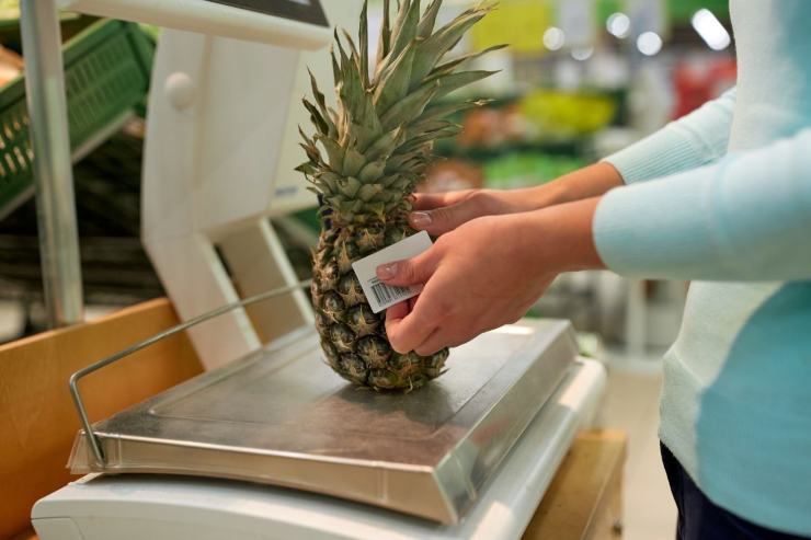 persona che pesa ananas al supemercato