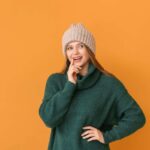 ragazza in posa con maglione verde e cappello beige