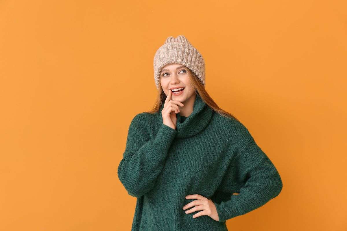 ragazza in posa con maglione verde e cappello beige