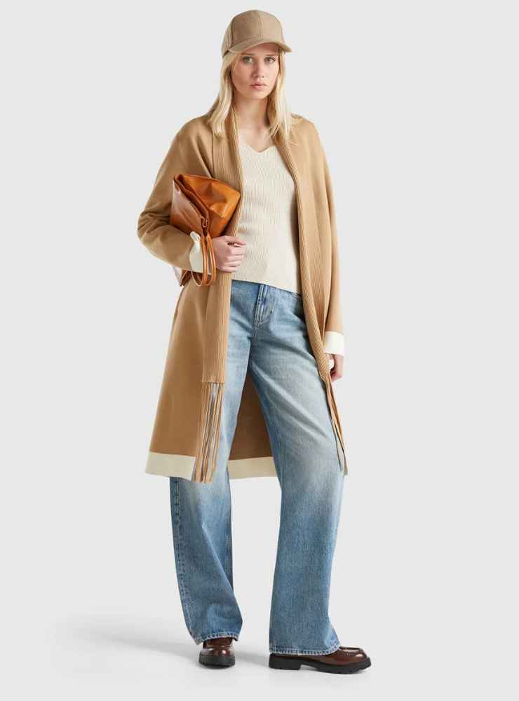 modella cappotto marrone con frange, maglia bianca, jeans e borsa da spalla marrone