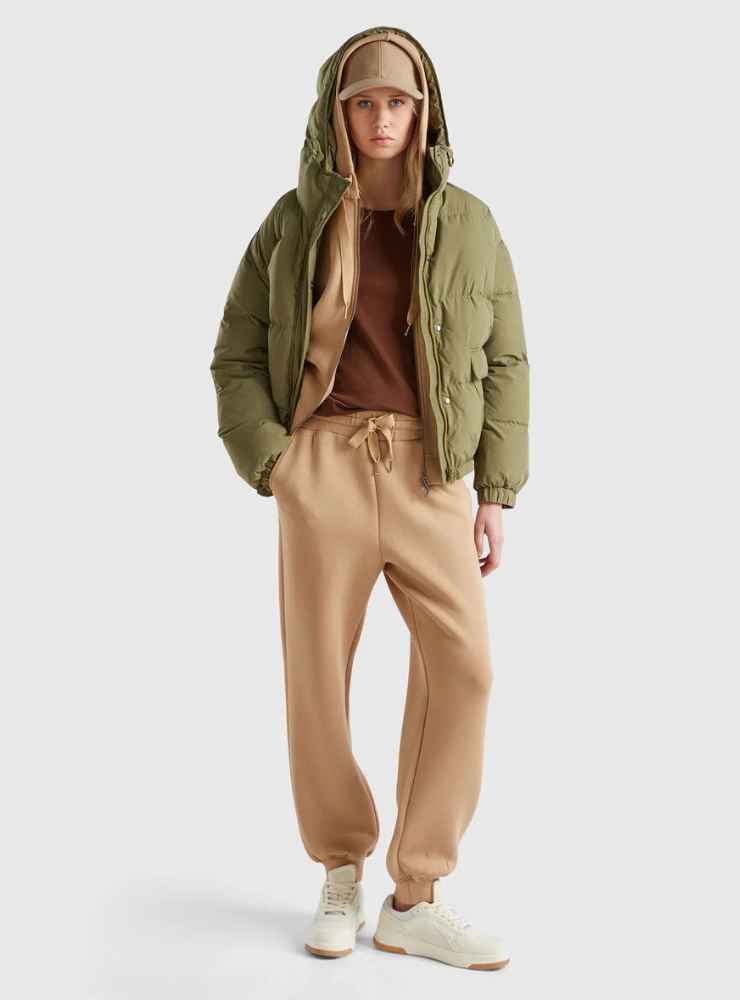 modella piumino e berretto verde, pantaloni sportivi e felpa beige 