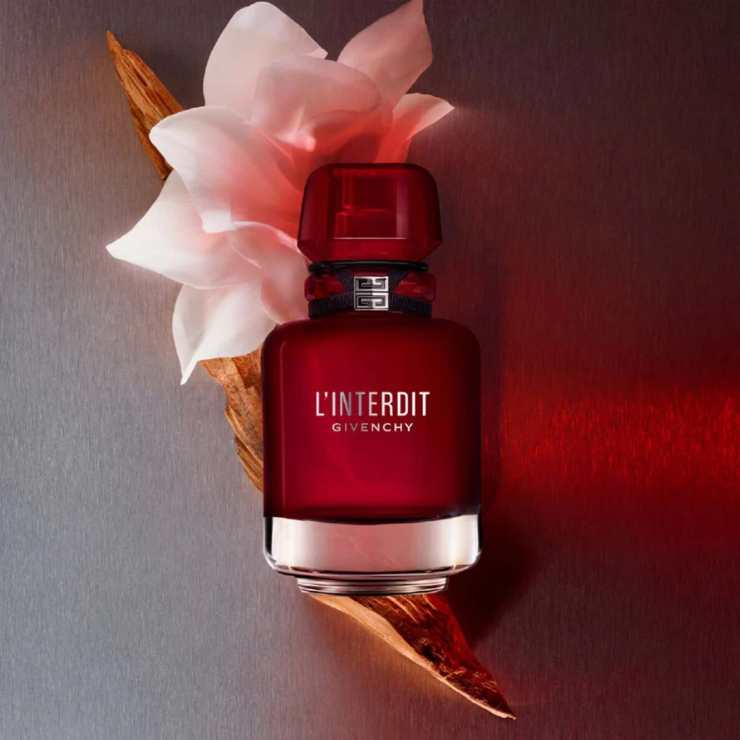 flacone rosso profumo e fiore