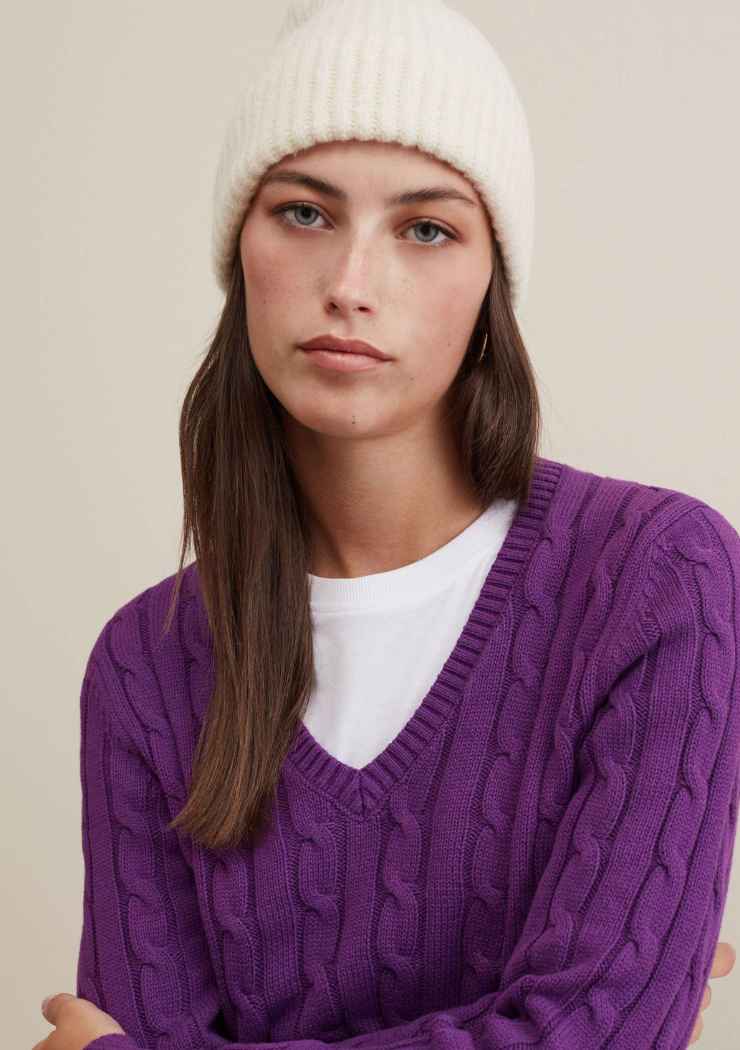 modella con pullover viola e cappellino di lana bianco