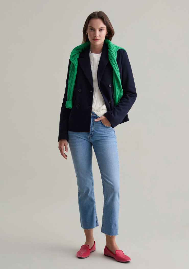 modella in jeans, maglietta bianca, blazer e pullover sulle spalle