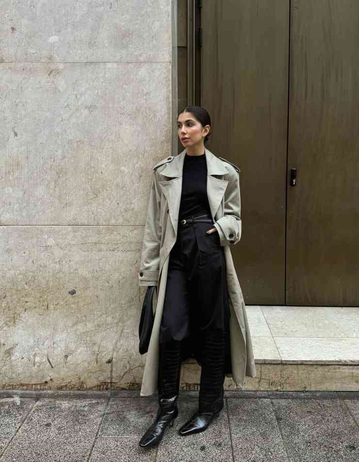 donna con trench, pantaloni neri e maglia nera