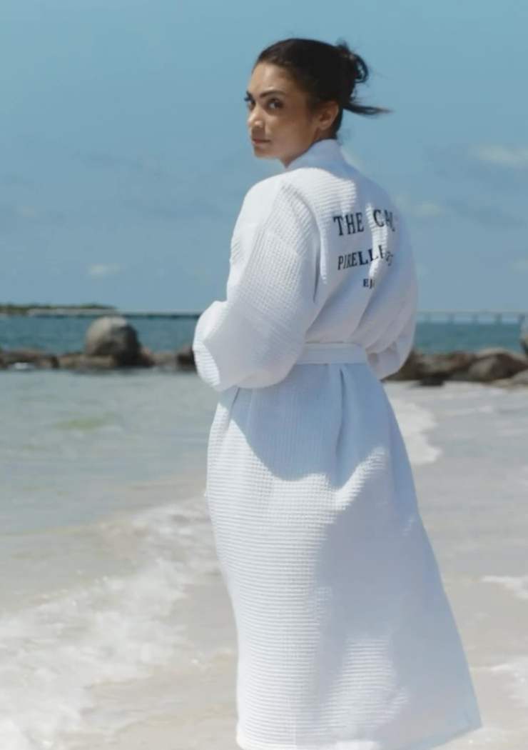 Elodie sulla spiaggia in accappatoio bianco