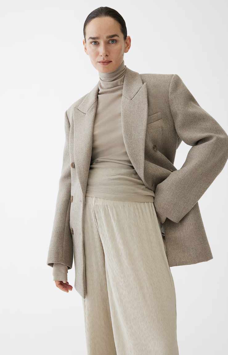 donna incinta con giacca oversize, maglione collo alto e pantaloni