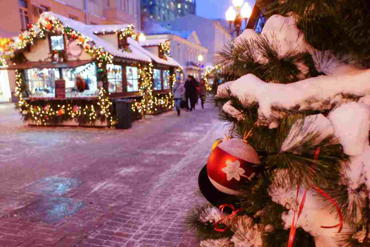 mercatino di natale con neve e albero addobbato in primo piano