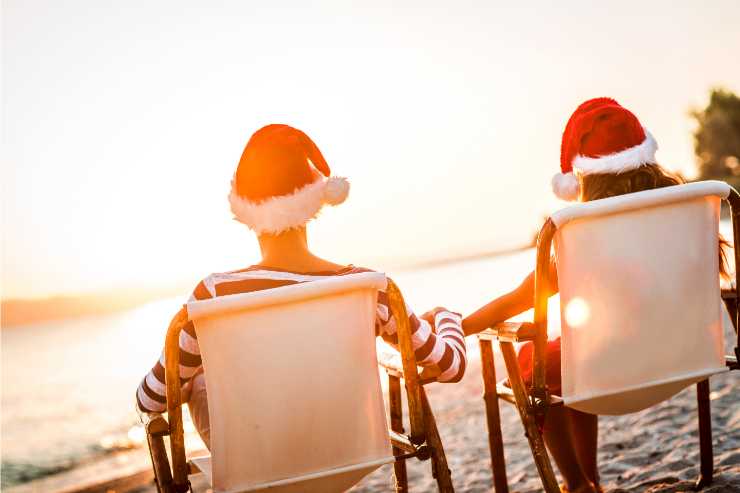 coppia di spalle sulla spiaggia con cappellini di Babbo Natale