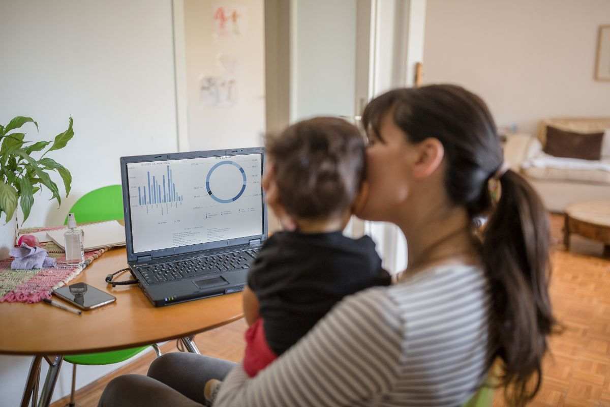 mamma con bambino di spalle che lavora al pc