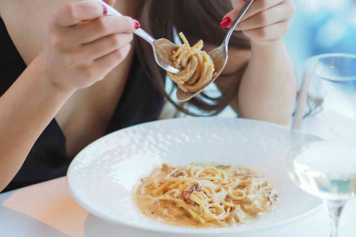 Ragazza che mangia spaghetti ala carbonara