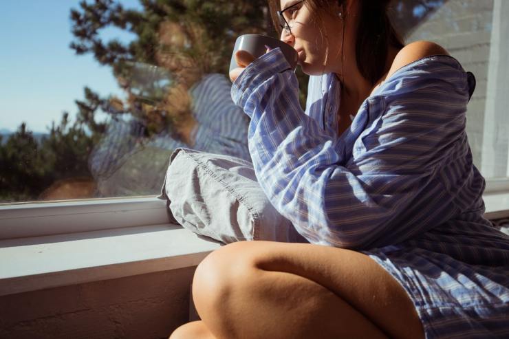 ragazza che beve e guarda fuori dalla finestra