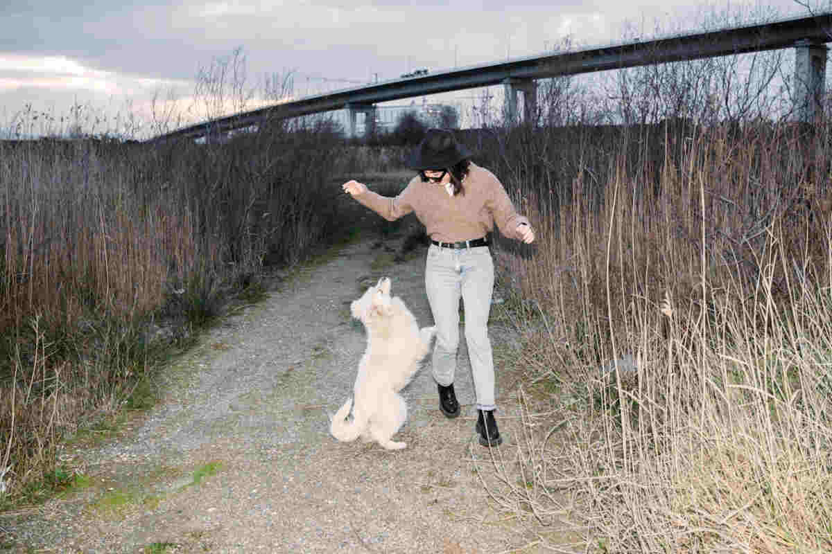 Ragazza con i jeans a vita alta che gioca con un cane