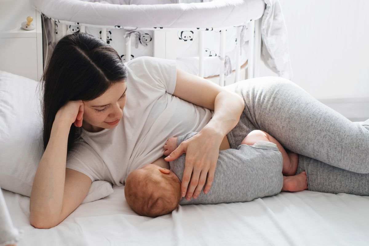 donna che allatta sdraiata sul letto