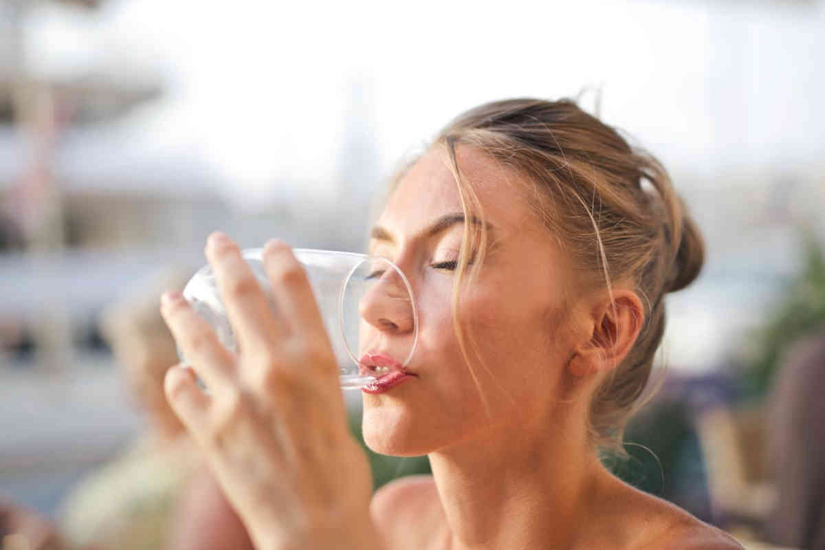 Donna che beve un bicchiere di acqua