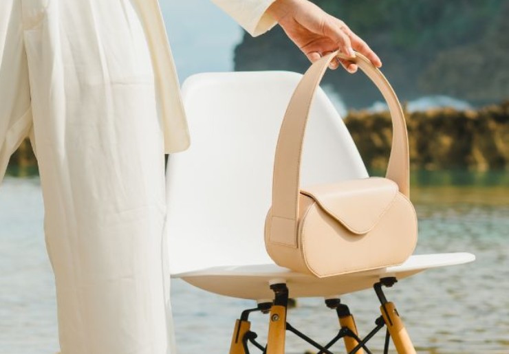 ragazza con borsa beige poggiata su una sedia