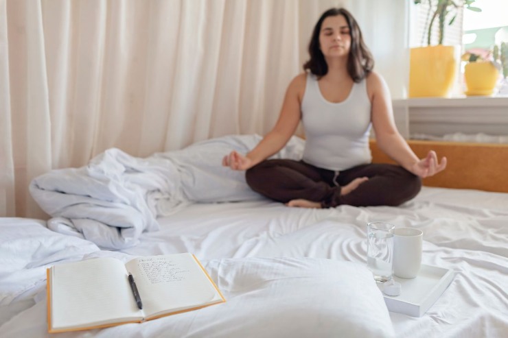 persona che medita sul letto con quaderno aperto