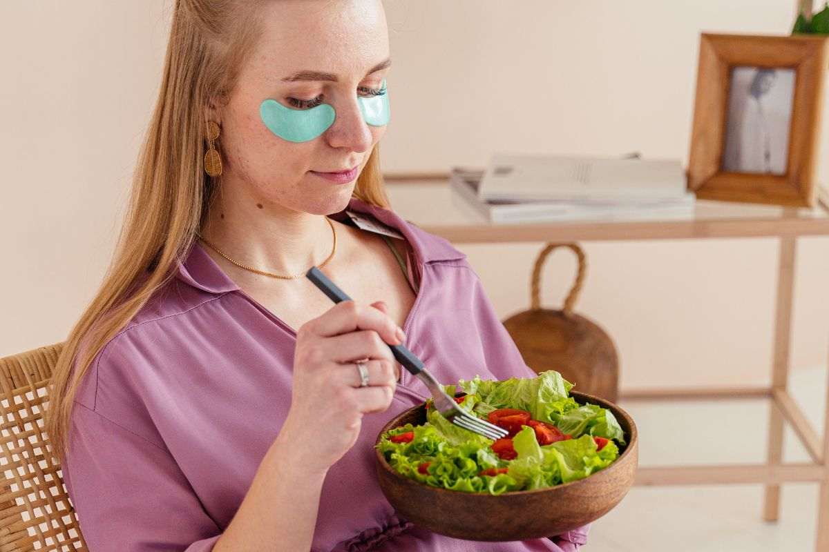 ragazza seduta con eye patch e ciotola di insalata in mano