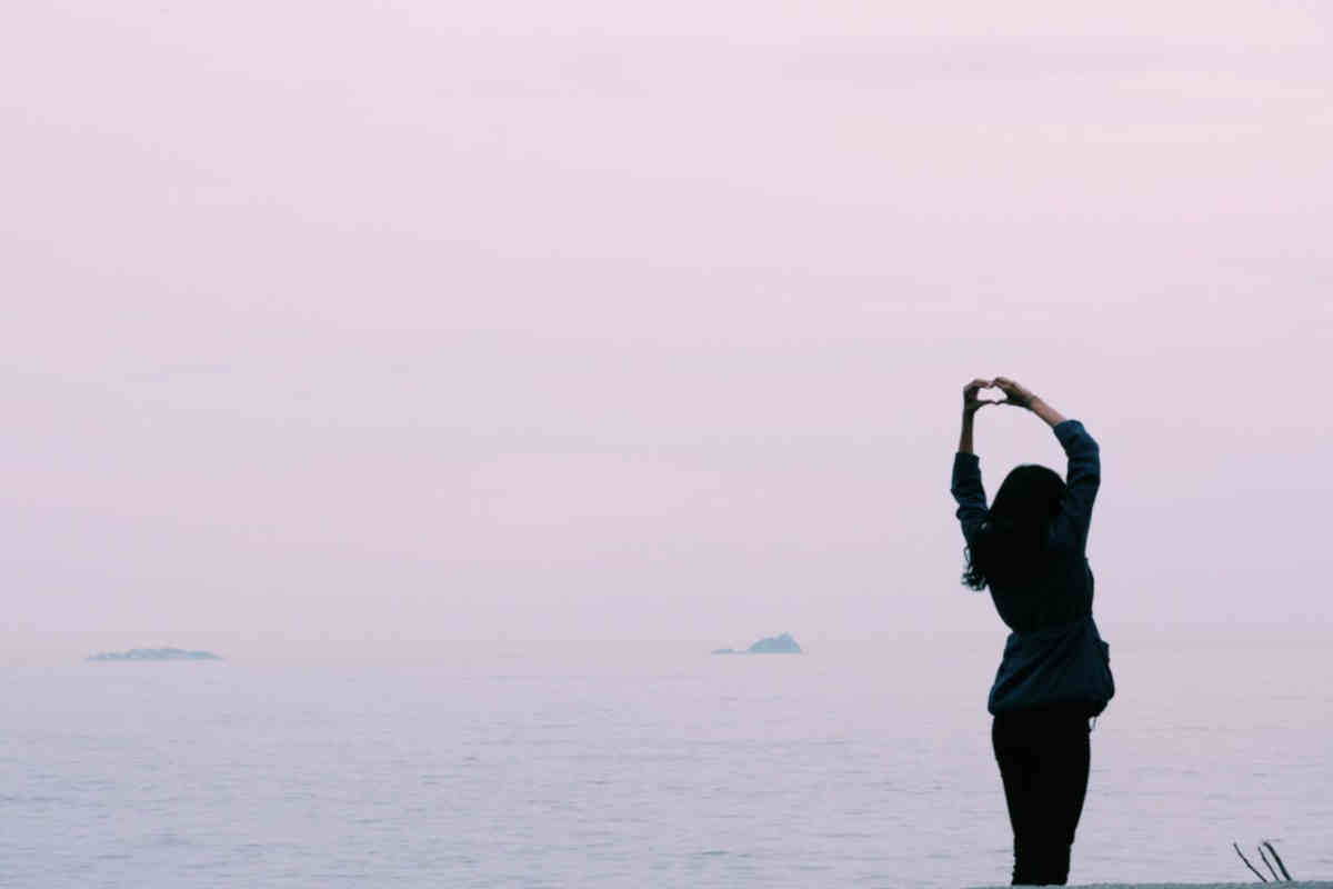 Ragazza che, di spalle, fa un cuore con le mani