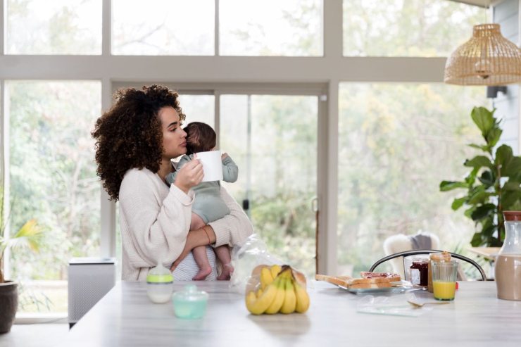 mamma con bambino in braccio mentre fa colazione in cucina