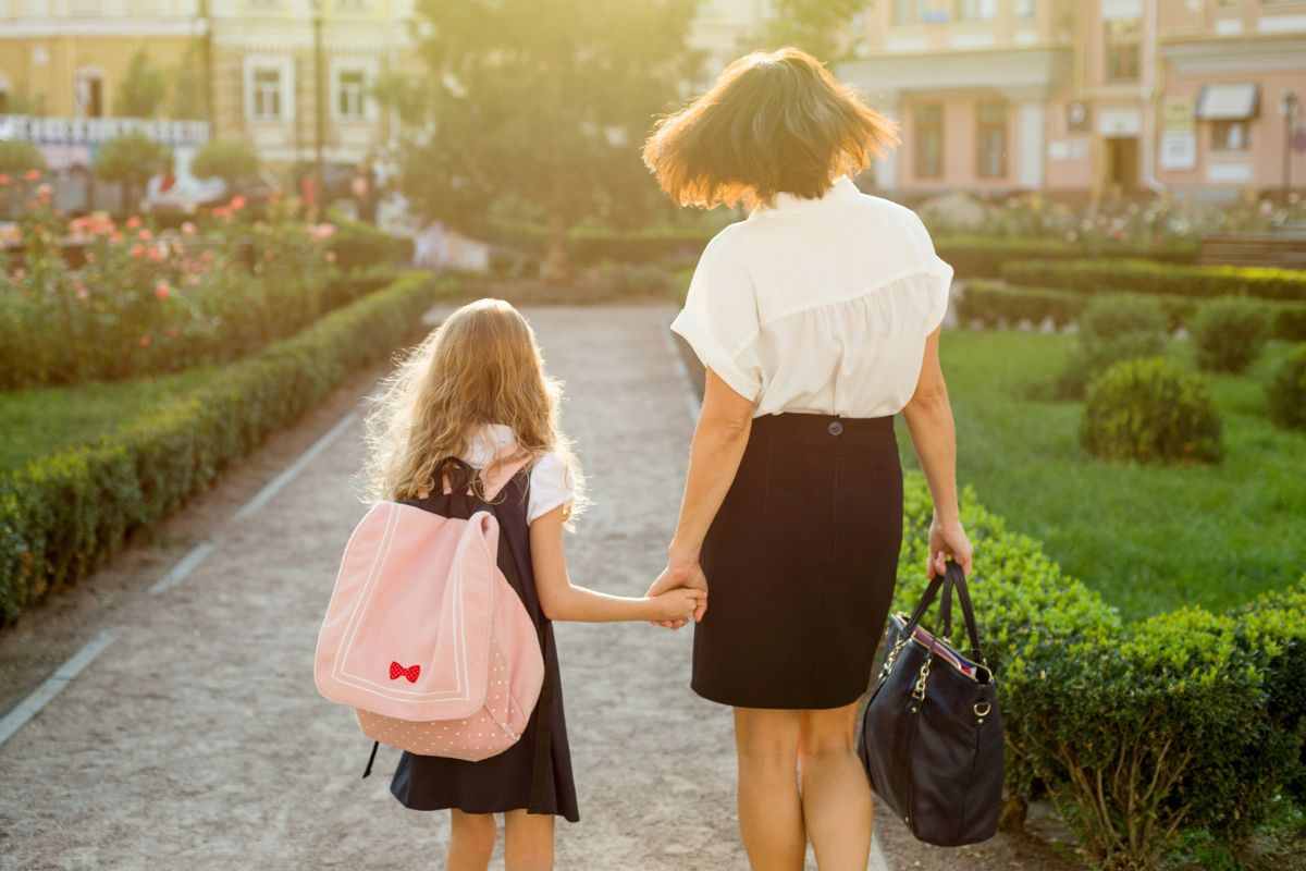 bambina che va scuola mano nella mano con la mamma