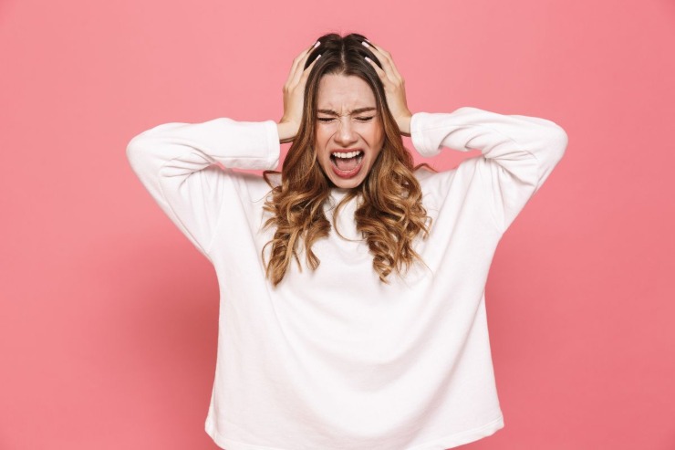 ragazza che urla con mani nei capelli 