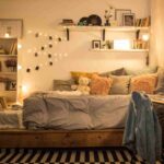 stanza in affitto con luci led, mensole, libreria e cuscini sul letto