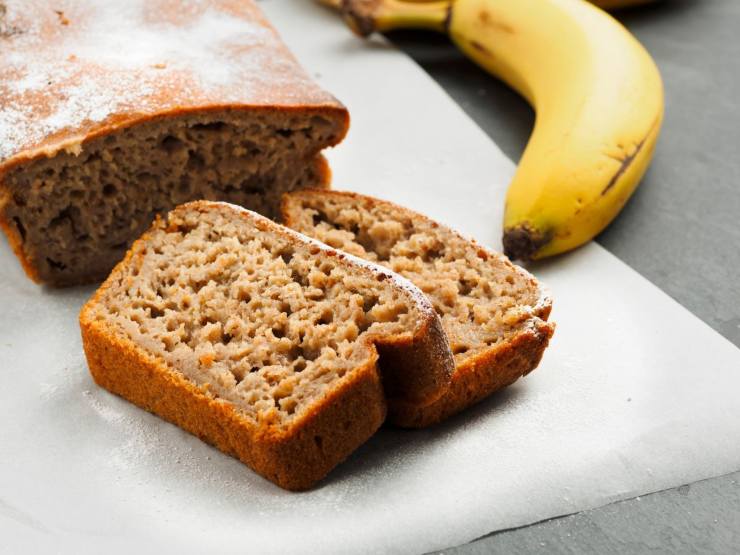 banana bread tagliato su tavolo con banana intera vicino