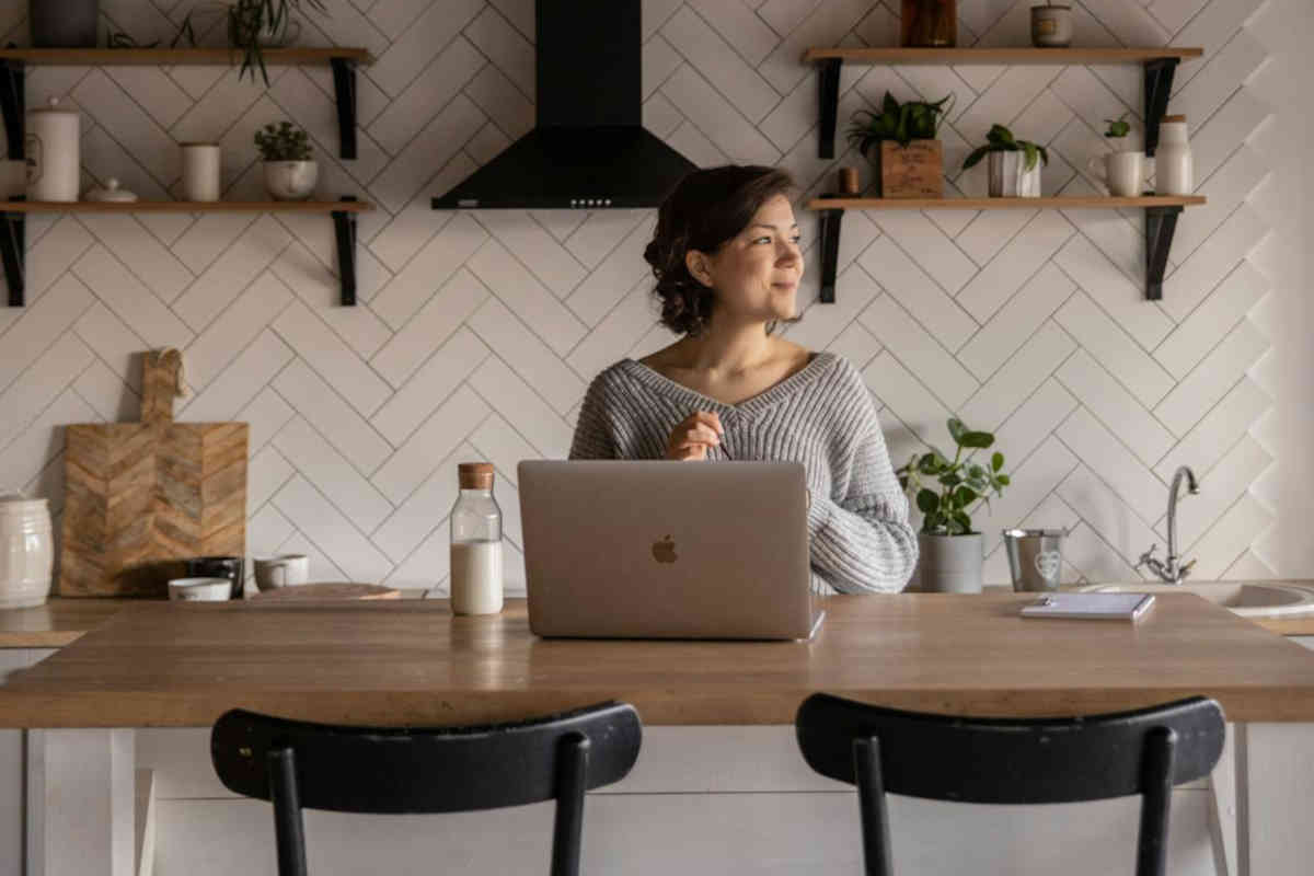 Donna seduta al tavolo in cucina davanti a un laptop