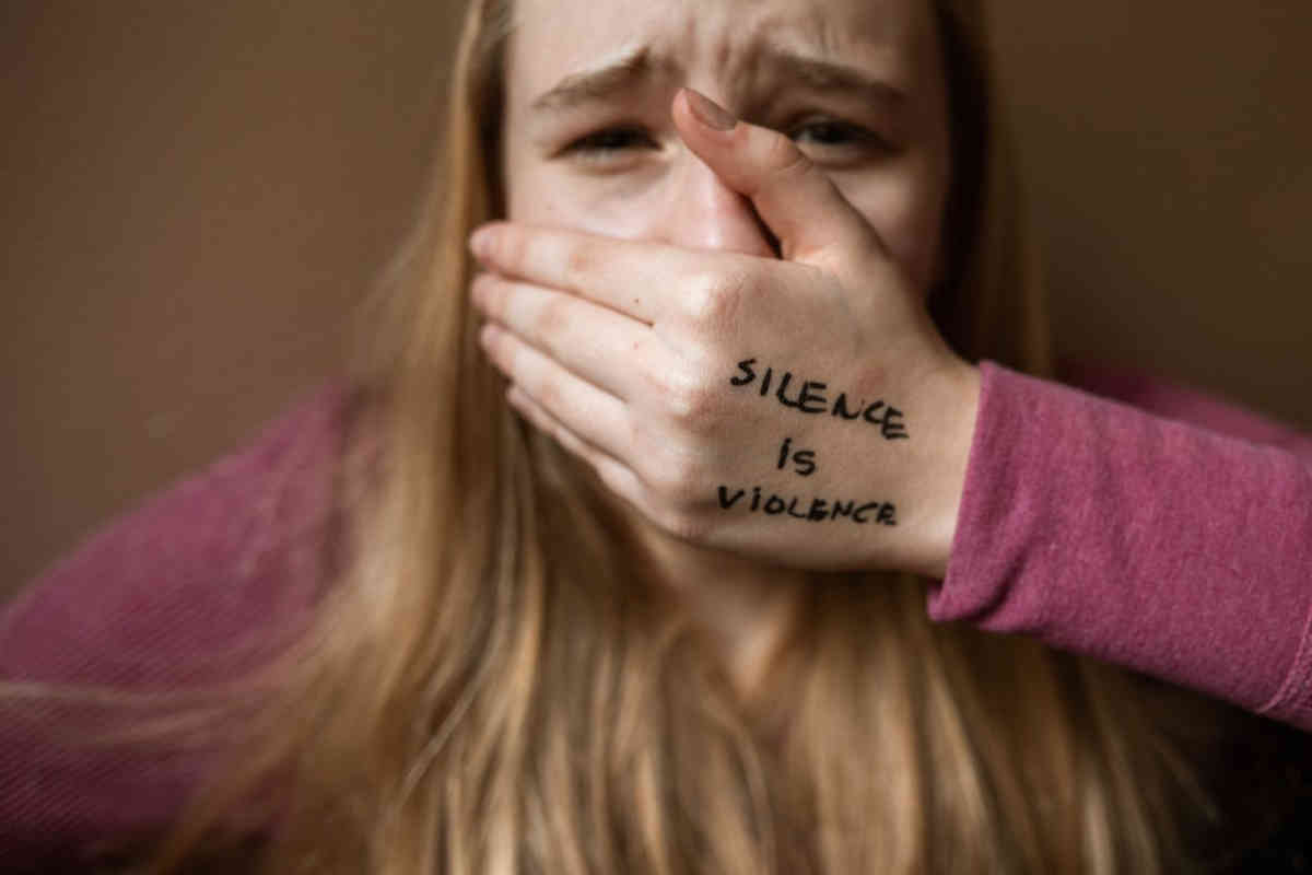 Ragazza che si silenzia con la mano in bocca