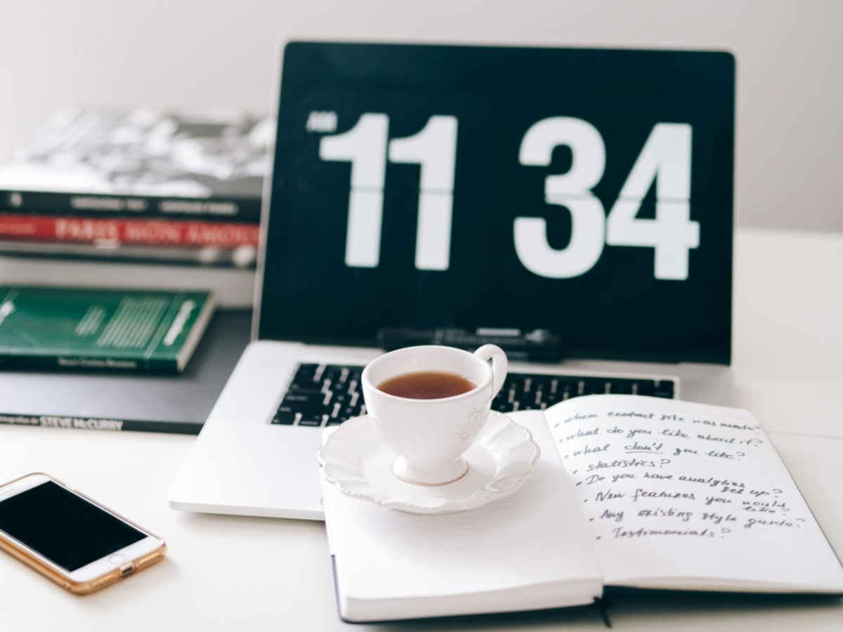 Postazione lavoro con laptop, agenda, tazza di tè e smartphone